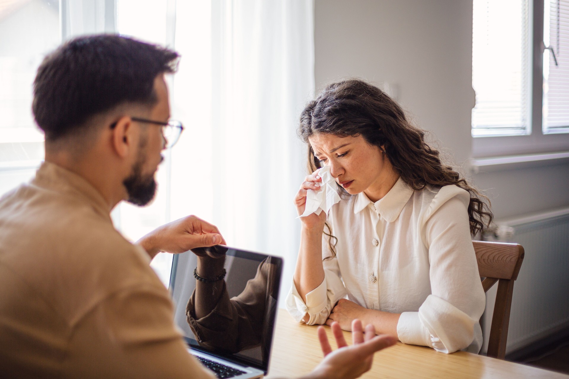 Psychologist comforting crying female patient during therapy session